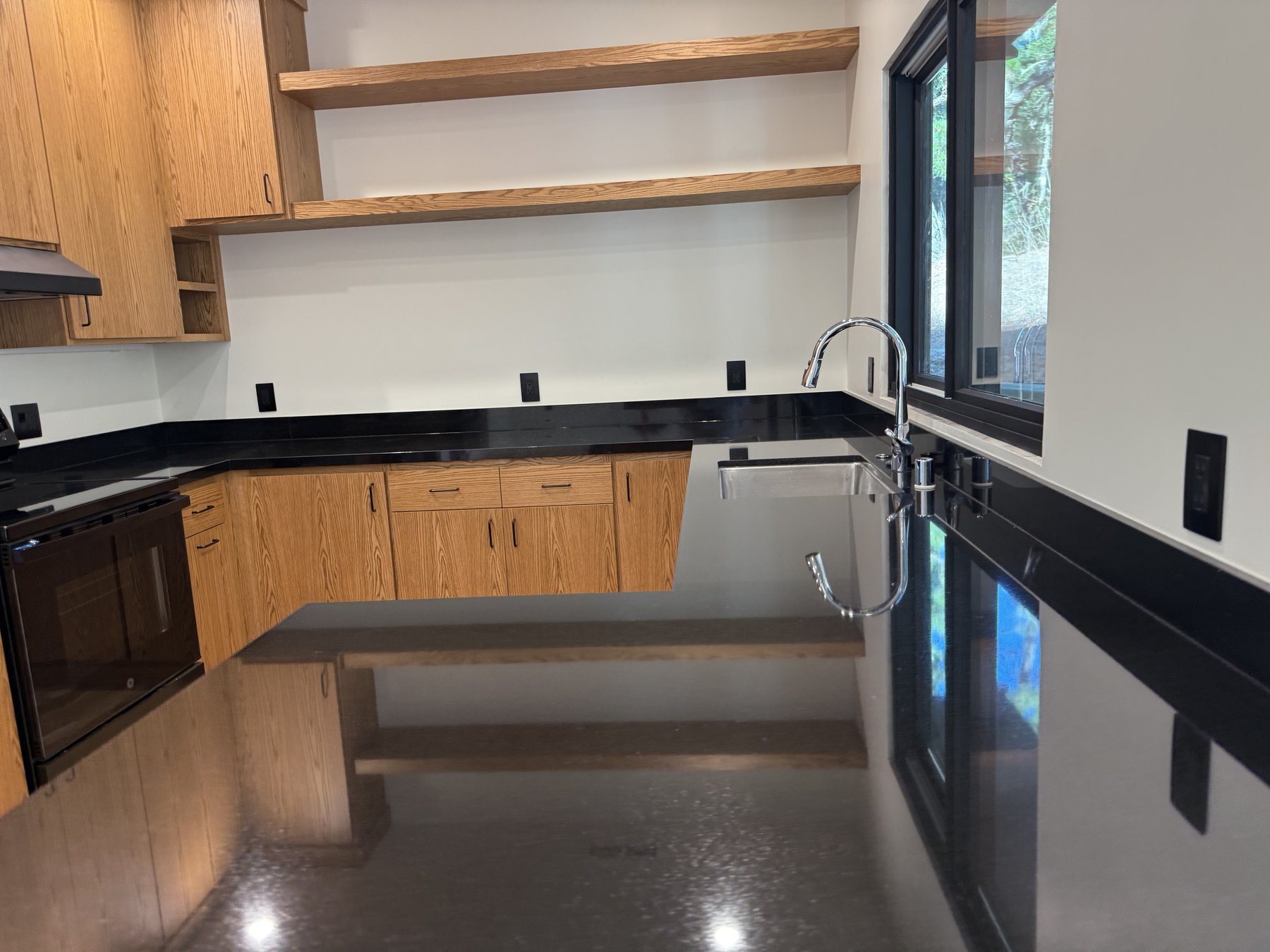 Custom kitchen remodel with wood cabinetry and black countertops in Monterey County