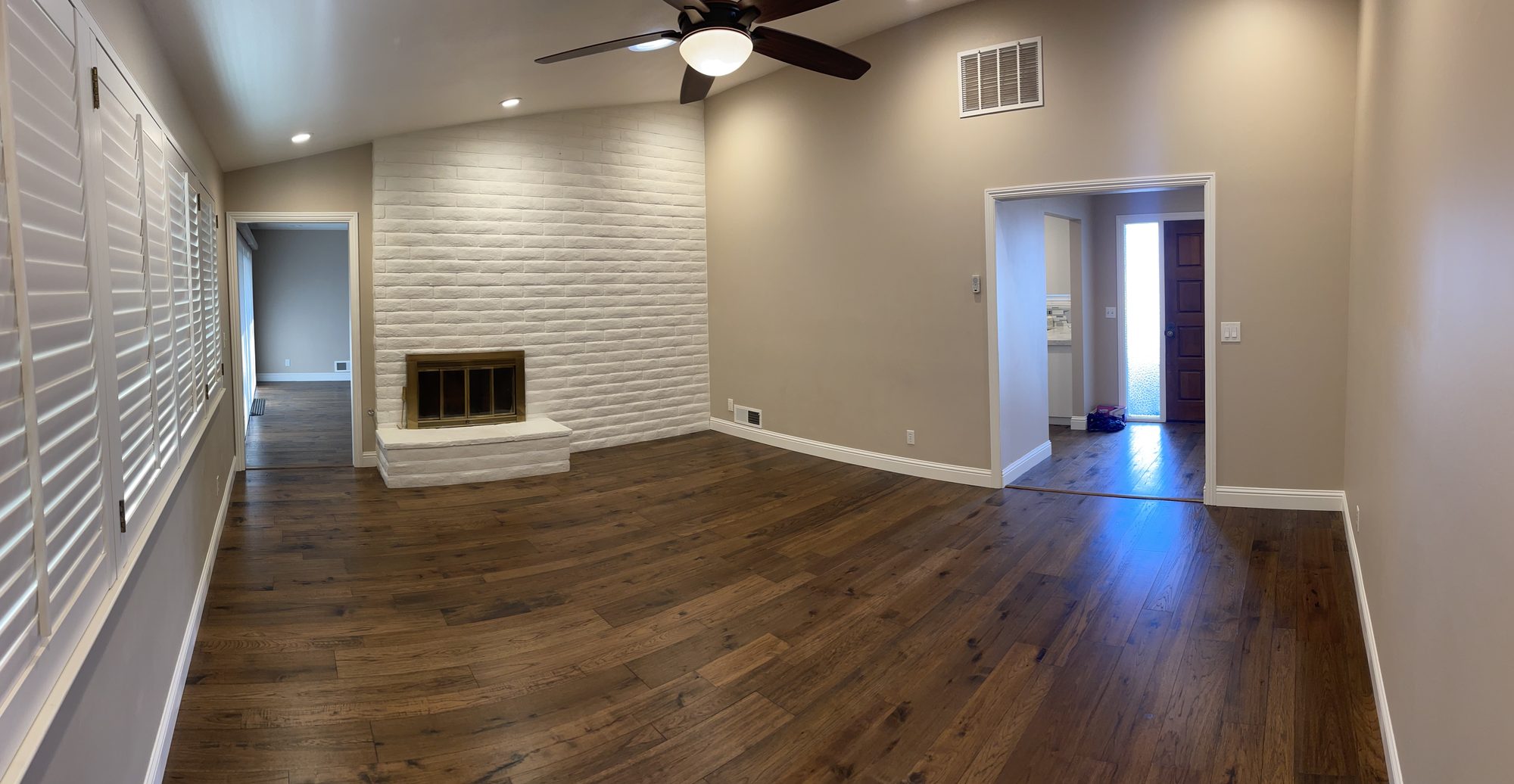 Open-plan living room remodel with hardwood floors and white brick fireplace